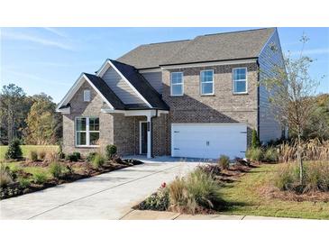 Charming two-story brick home with attached garage and professionally landscaped front yard under a clear blue sky at 610 Belshire Dr, Acworth, GA 30102