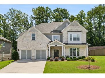 Charming two-story brick home featuring a three-car garage, manicured lawn, and mature landscaping at 614 Denali Dr, Mableton, GA 30126