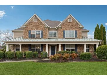 Traditional two-story brick home featuring a covered front porch and lush landscaping at 1527 Sage Ridge Dr, Marietta, GA 30064