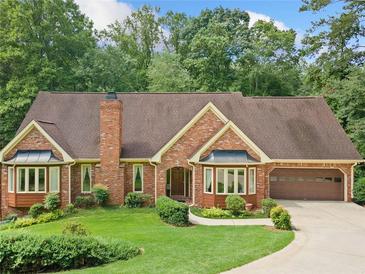 Charming brick home featuring bay windows, attached garage, and lush lawn at 3436 Laurelwood Ne Ct, Roswell, GA 30075