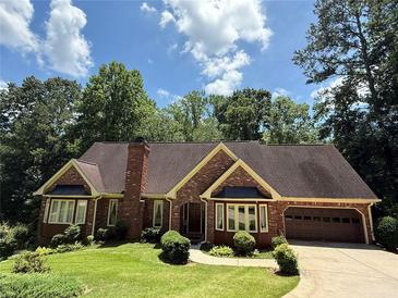 Charming brick home with manicured lawn, mature trees, and attached two-car garage at 3436 Laurelwood Ne Ct, Roswell, GA 30075