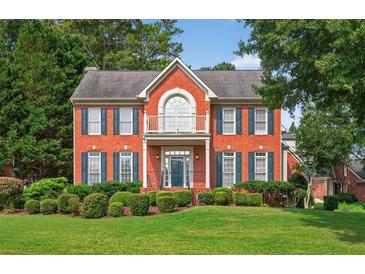 Charming red brick two-story home featuring a beautiful balcony, manicured lawn, and mature landscaping at 2559 Dunhaven Gln, Snellville, GA 30078