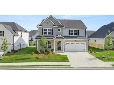 Charming two-story home with grey and white brick exterior, a well-manicured lawn, and a two car garage at 13568 Whitman Lane, Covington, GA 30014