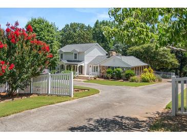 Charming two-story home with a white picket fence, mature trees, and a well-manicured lawn at 2166 Tanglewood Dr, Snellville, GA 30078