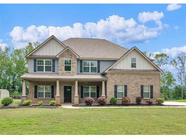 Charming two-story brick home with a covered porch, manicured lawn, and beautiful landscaping at 149 Elkins Blvd, Locust Grove, GA 30248