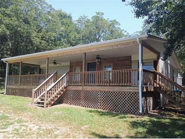 Charming house featuring a large covered porch and natural wood accents, set in a serene, wooded environment at 393 W Freeman St, Maysville, GA 30058