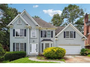 Charming two-story home with a well-manicured lawn, lush greenery, and attached garage at 4467 Boatmans Cv, Stone Mountain, GA 30083