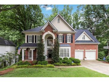 Inviting two-story brick home featuring a manicured lawn, mature trees, and a two-car garage at 2200 Major Loring Sw Way, Marietta, GA 30064