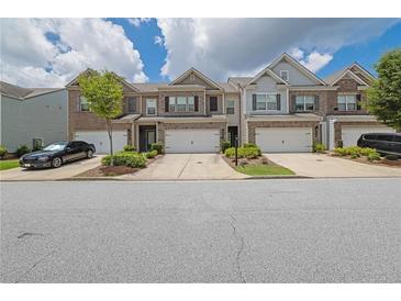 Charming townhomes with brick accents, attached garages, and well-maintained landscaping on a sunny day at 2638 Village Park Bnd, Duluth, GA 30096
