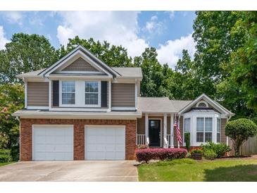 Charming two-story home featuring a two-car garage, a landscaped yard, and a welcoming front porch with an American flag at 1115 Manor Nw Way, Kennesaw, GA 30144