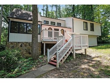 Charming white two-story home featuring a spacious front deck and stone accents, surrounded by lush trees at 3038 Skidaway Ct, Stone Mountain, GA 30087
