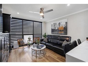 Stylish living room featuring a modern ceiling fan, zebra pillows, and hardwood floors at 1280 W Peachtree W St, Atlanta, GA 30309