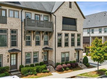 Charming brick townhome with a balcony, manicured landscaping, and inviting curb appeal at 2447 Figaro Dr, Atlanta, GA 30339