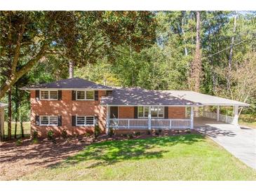 Charming brick home with a covered front porch and carport, nestled among mature trees at 504 Milligan Dr, Stone Mountain, GA 30083