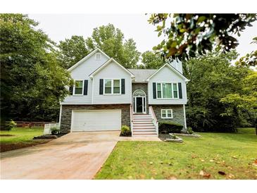 Charming two-story home with stone accents, a well-manicured lawn, and inviting staircase at 7030 Wessex Way, Cumming, GA 30028