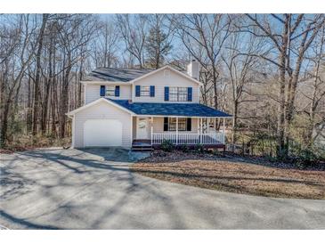 Charming two-story home with a welcoming front porch and a spacious driveway nestled among trees at 169 Holly Ct, Loganville, GA 30052