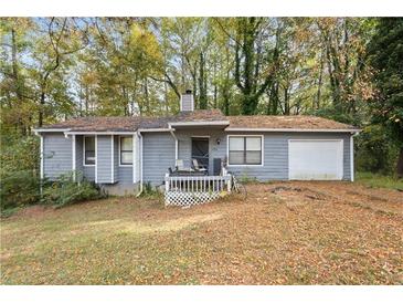 Charming single-story home featuring gray siding, front porch and attached garage, surrounded by mature trees at 1496 Meadowlark Dr, Decatur, GA 30032