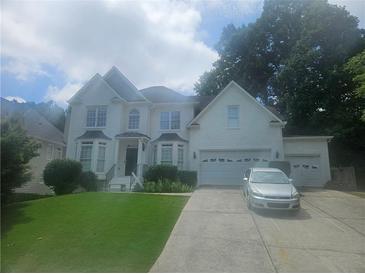 Elegant white brick home with a manicured lawn, multiple car garage, and a beautiful front entrance at 9035 Sandorn Dr, Roswell, GA 30075