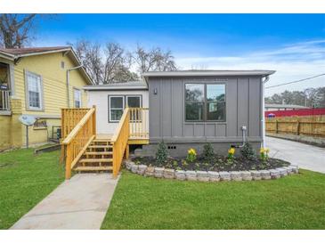 Charming home featuring new wood deck, landscaped flower bed, and a well maintained green lawn at 1 Lamar Ave Sw, Atlanta, GA 30310
