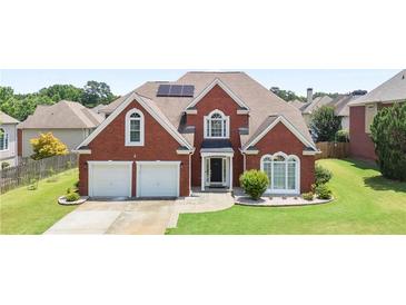 Charming two-story brick home features a well-manicured lawn and two-car garage at 3735 Turnbury Oaks Dr, Peachtree Corners, GA 30096