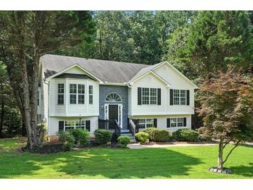 Charming home with white siding, black shutters, and a beautifully landscaped front yard with mature trees at 4076 Whistler Dr, Douglasville, GA 30135
