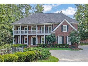 Elegant two-story brick home showcasing a manicured lawn, mature trees, and welcoming curb appeal at 8935 Muirfield Ct, Duluth, GA 30097