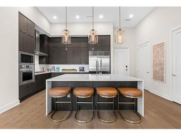 Modern kitchen boasts a large island with seating, stainless steel appliances and stylish pendant lighting at 40 12Th St # 1004, Atlanta, GA 30309