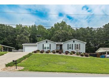 Charming single-story home with a well-manicured lawn and a driveway leading to an attached garage at 2711 Bluffton Rd, Buford, GA 30519