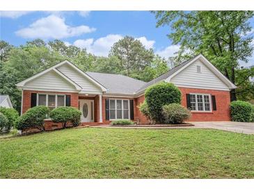 Charming red brick home featuring a well-manicured lawn and mature landscaping at 1721 Druids Se Xing, Conyers, GA 30013