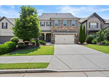 Charming two-story home featuring a stone and siding facade, a two-car garage, and a well-manicured lawn at 4452 Thach Ave, Sugar Hill, GA 30518