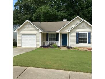 Charming single-story home with a well-manicured lawn, blue shutters, and an attached garage at 469 Village Cir, Stockbridge, GA 30281