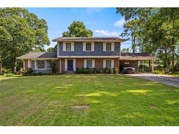 Charming two-story home with a lush green lawn, mature trees and a covered carport at 1809 Claron Ave, Conley, GA 30288