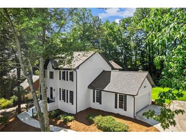 Elegant two-story home with painted brick exterior and black shutters surrounded by mature trees at 4745 Masters Ct, Duluth, GA 30096