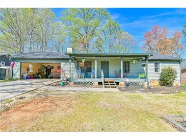 Charming single-story home with a covered front porch and open garage on a sunny day at 5774 Harbor Dr, Buford, GA 30518