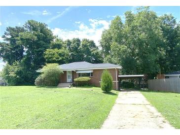 Cozy single-story home with a carport, mature trees, and a well-manicured lawn at 1024 Magnolia Dr, Smyrna, GA 30082