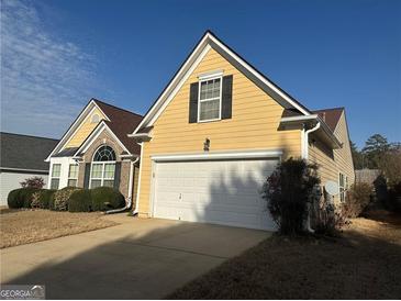 Charming yellow home with well-manicured landscaping and a two-car garage on a sunny day at 1060 S Creek Dr, Villa Rica, GA 30180