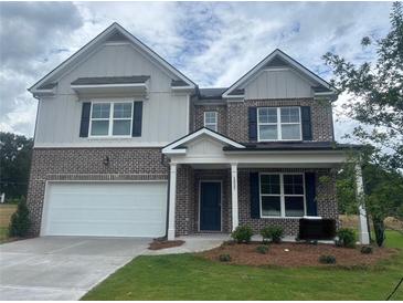 Two-story brick home with a white garage door, black shutters, and a well-manicured lawn at 1857 Kingsmere Run Dr, Loganville, GA 30052