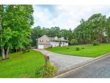 Charming two-story home with a well-manicured lawn and a long driveway leading to the garage at 1137 Eagles Nest Cir, Carrollton, GA 30116