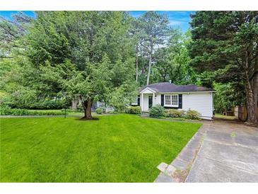 Charming single-story home featuring a well-manicured lawn, mature trees, and a classic white exterior at 1091 Napier St, Atlanta, GA 30316