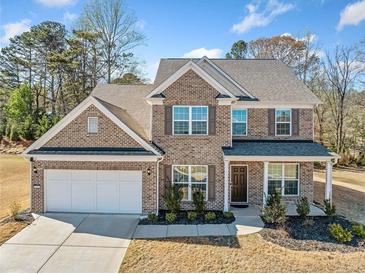 Beautiful two-story brick home with a manicured lawn, covered porch, and a two-car garage at 3505 Aqua Point Pl, Cumming, GA 30041