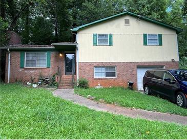 Charming split-level home featuring a brick facade and a well-maintained front yard with mature trees at 2275 Chestnut Log Loop, Lithia Springs, GA 30122