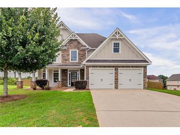Charming two-story home featuring a stone facade, attached two-car garage, and a beautifully landscaped front yard at 70 Trinity Lane, Covington, GA 30016
