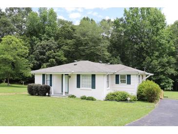 Charming single-story home with a well-maintained lawn and classic white facade, complemented by lush green landscaping at 9916 Stockmar Rd, Villa Rica, GA 30180