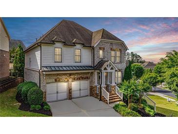 Charming two-story home featuring a two-car garage and beautifully landscaped front yard with stone and siding accents at 11760 Stratham Dr, Alpharetta, GA 30009