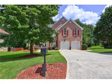 Charming two-story brick home with red shutters, two-car garage, and lush landscaping at 6812 Danforth Way, Stone Mountain, GA 30087