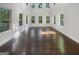 Bright living room with dark wood floors, white walls, and many windows with views of the surrounding greenery at 819 Bermuda Run, Woodstock, GA 30189