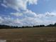 View of land with sparse grass, a tree line in the distance, and blue skies with puffy white clouds above at 0 Hawkins Academy Rd, Social Circle, GA 30025