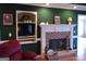 A traditional living room featuring a brick fireplace, built in shelving, dark green walls, and hardwood floors at 0 Hawkins Academy Rd, Social Circle, GA 30025