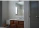 Bathroom with wood vanity, sink, large mirror, and white wire shelving for storage at 207 Millwheel Dr, Villa Rica, GA 30180