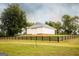 Exterior view of a charming white barn with a black fence, set against a backdrop of green fields and trees at 1875 Highway 142 E, Covington, GA 30014